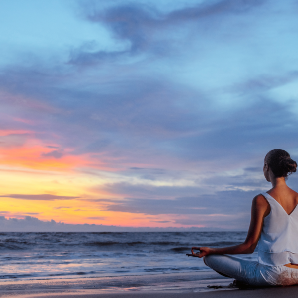 photo showing a meditating lady sitting by the beach