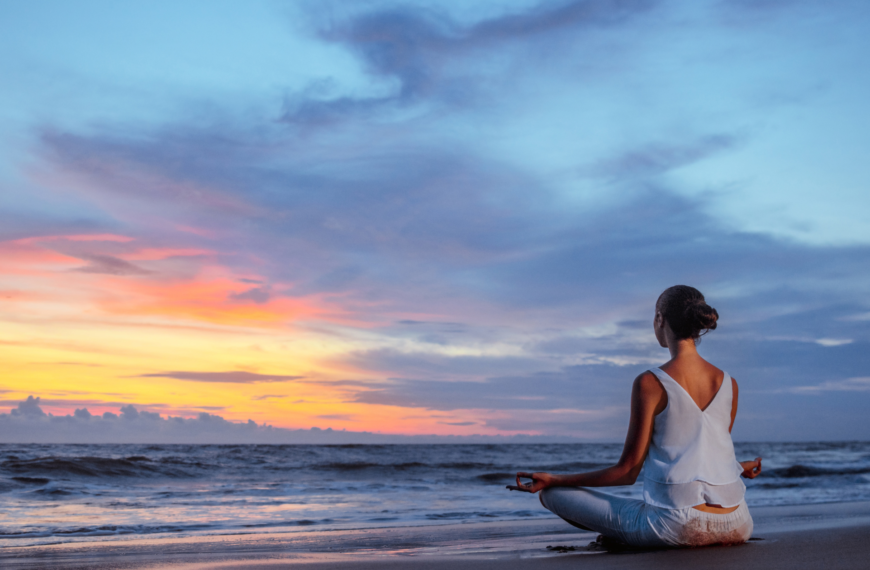 photo showing a meditating lady sitting by the beach